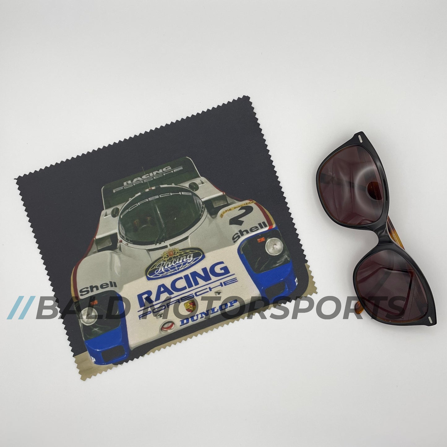 Produkt-Bundle bestehend aus Modellauto Porsche 956 LH Sieger Le Mans 1982 im Maßstab 1:18 inklusive passender Keramiktasse und Brillenputztuch